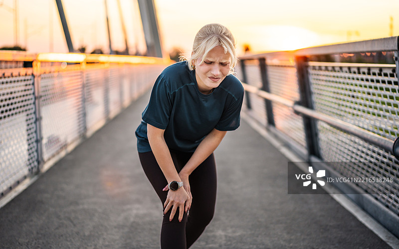 年轻的运动女性在户外跑步后膝盖疼痛图片素材