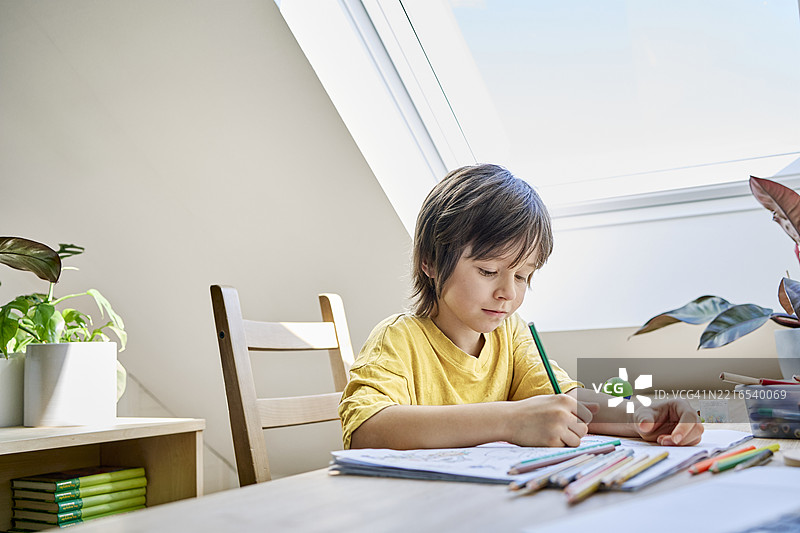 男孩在窗边用彩色铅笔画画图片素材