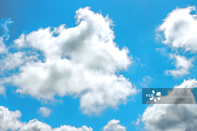 阳光明媚的日子里，明亮的蓝天上飘着蓬松的白云图片素材