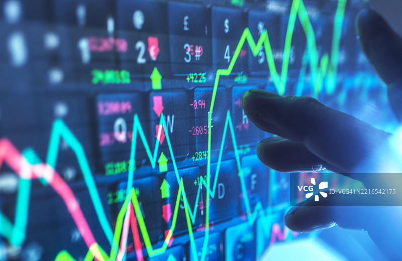 手与数字屏幕上的金融数据互动，显示股票市场图表图片素材