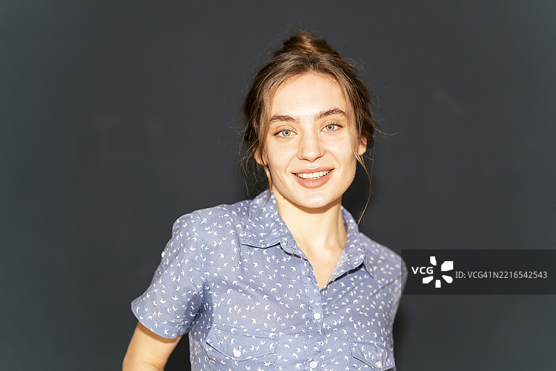 穿着蓝色衬衫的微笑女性在阁楼公寓内摆姿势图片素材