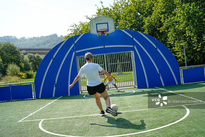 母亲和儿子在阳光明媚的日子里踢足球图片素材