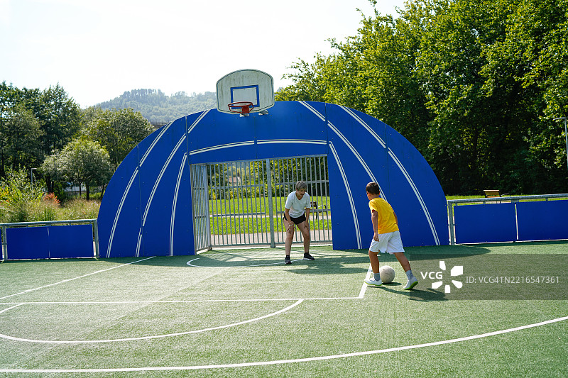 祖母在户外球场指导孙子踢足球图片素材