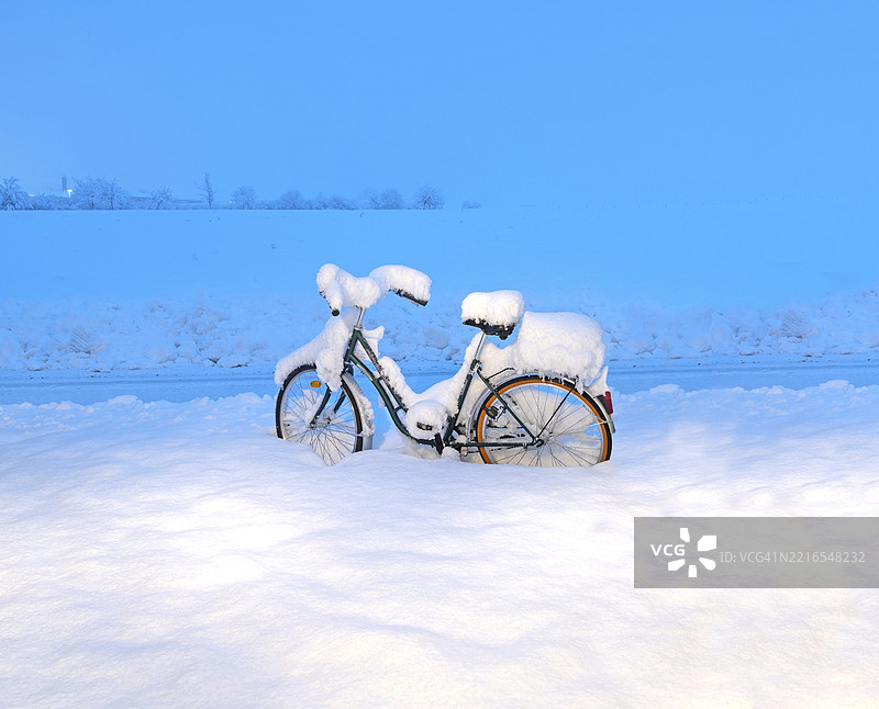 覆盖着雪的巡洋舰风格自行车在德国下巴伐利亚州普拉特林的深雪中静静伫立，清晨的十二月。图片素材