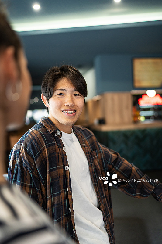 年轻男子在咖啡馆里微笑着与朋友交谈图片素材