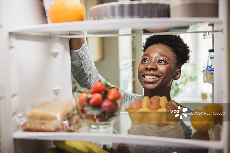 女人从装满杂货的冰箱里拿食物图片素材