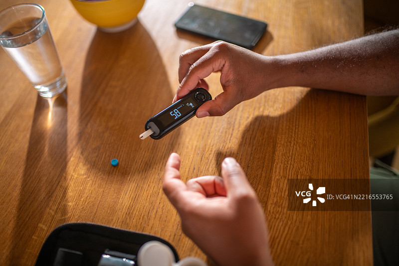 中年西班牙裔男性在明亮的家居环境中检查血糖水平图片素材