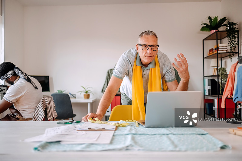 在裁缝店工作的人们使用笔记本电脑作为辅助工具图片素材