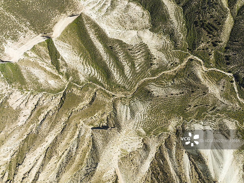 戈拉费沙漠中的泥土道路，经过几场降雨后周围绿意盎然，鸟瞰图，航拍，联合国教科文组织格拉纳达地质公园，西班牙安达卢西亚省格拉纳达。图片素材