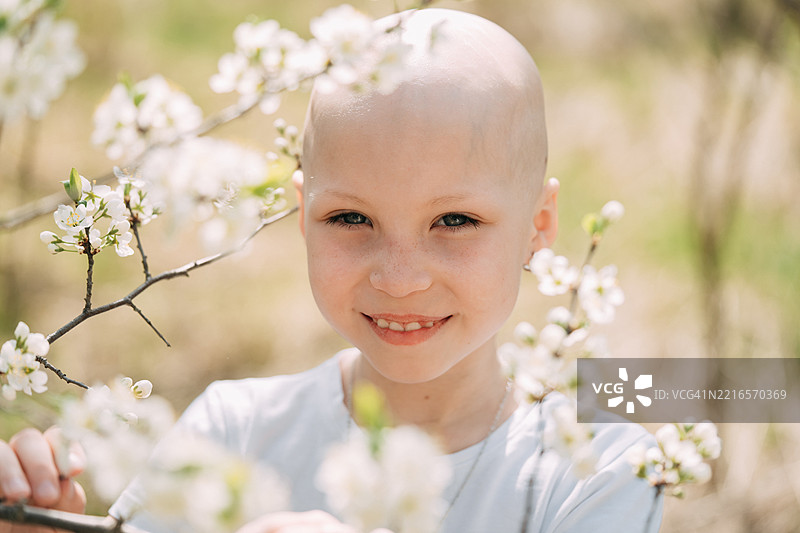 光头孩子在春天微笑着触摸盛开的树枝图片素材