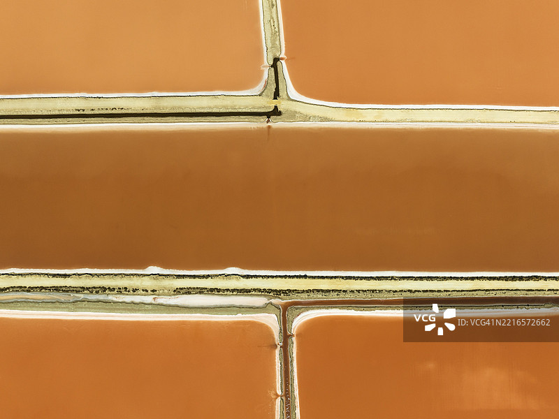 位于圣卢卡尔·德·巴拉梅达附近的博南萨盐场的盐水池。橙红色的颜色取决于盐度水平，直接由盐藻（Dunaliella salina）和盐水虾引起。鸟瞰图。无人机拍摄。西班牙安达卢西亚省卡迪斯。图片素材