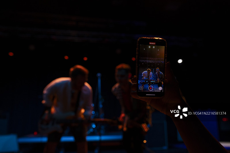 一位粉丝用手机从观众席录制她最喜欢的乐队的表演图片素材