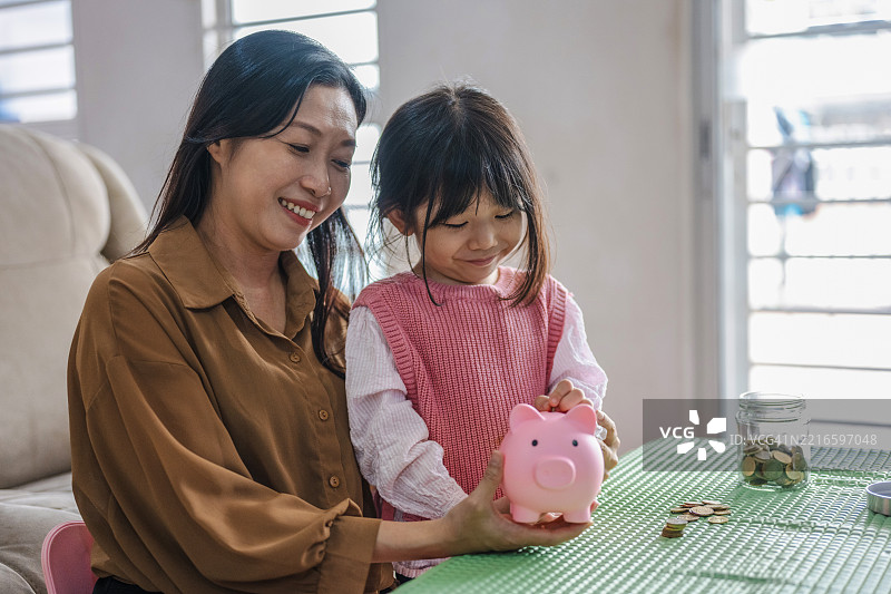 小孩把硬币放进储蓄罐里图片素材