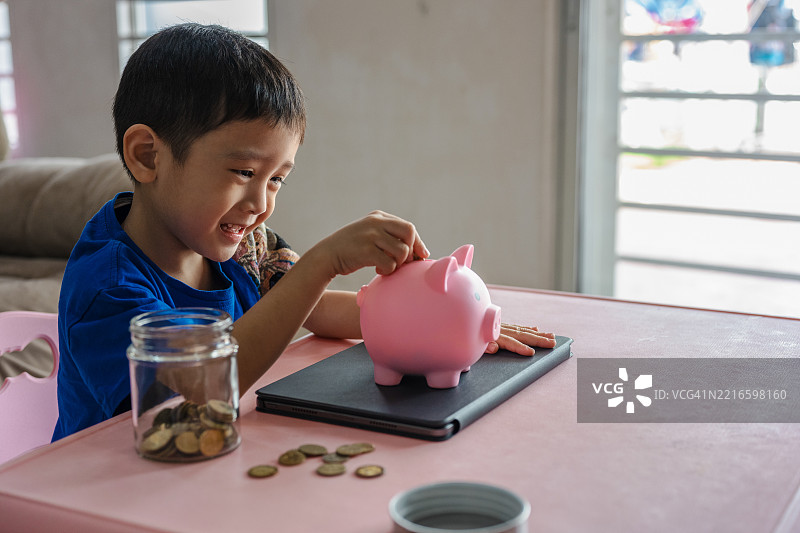 孩子把硬币放进储蓄罐里图片素材