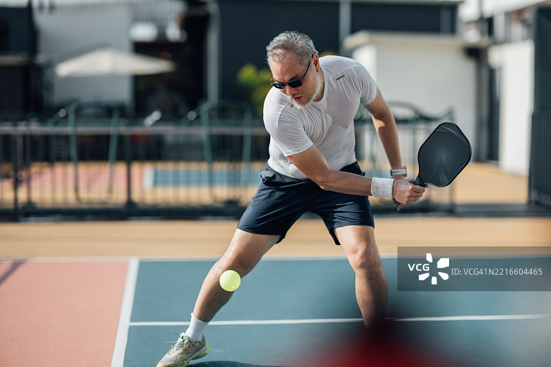 掌握反手击球：一位成熟运动员在户外皮克球比赛中的热情表现图片素材