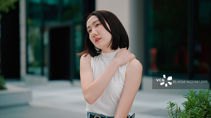 年轻的亚洲女性在过度劳累后为自己按摩，缓解肌肉酸痛。图片素材