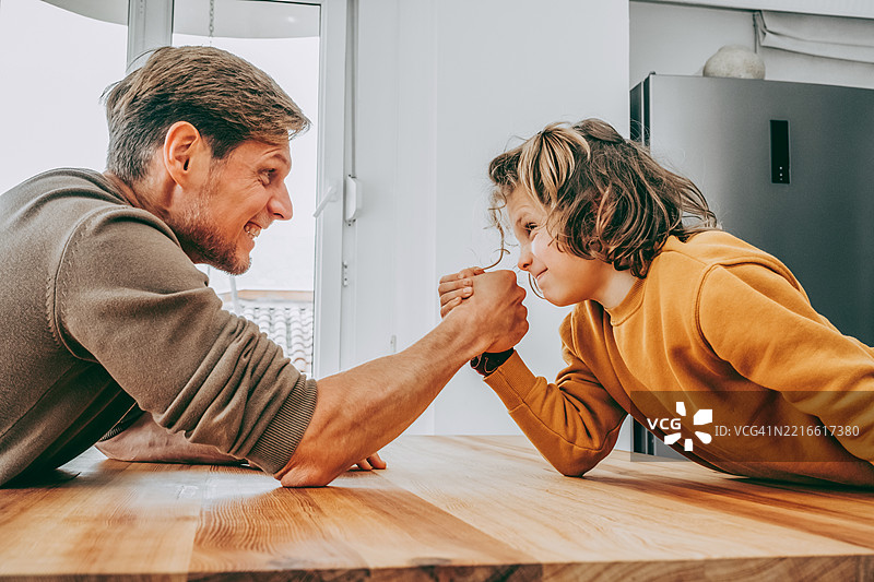 父亲与青少年儿子进行摔跤比赛，家庭共度时光图片素材