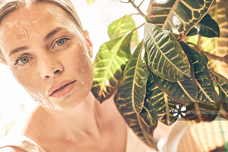 特写肖像，一位美丽的金发女性脸上涂抹胶原蛋白，美容概念。图片素材