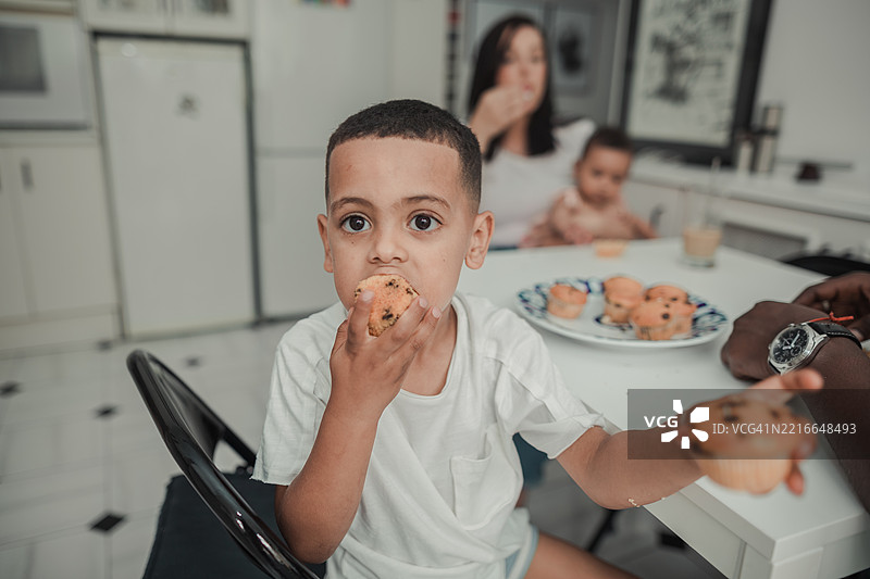 非洲男孩一边吃松饼一边看着镜头图片素材