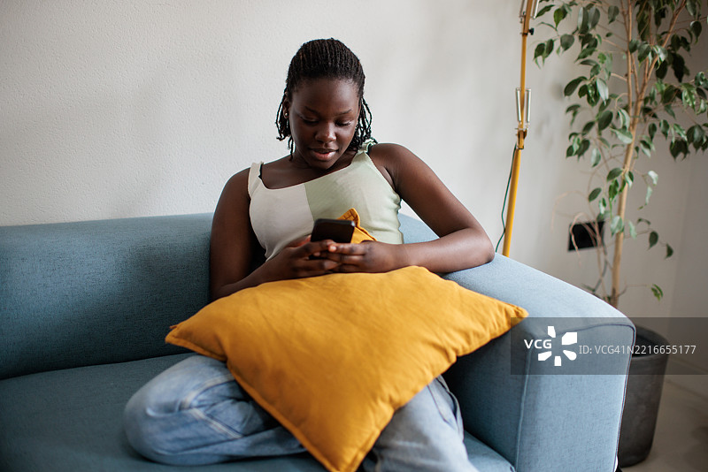 女人坐在沙发上浏览手机图片素材