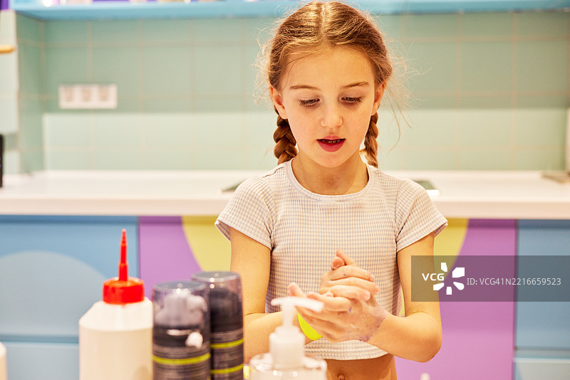 小女孩在五彩缤纷的浴室里小心翼翼地用肥皂洗手图片素材