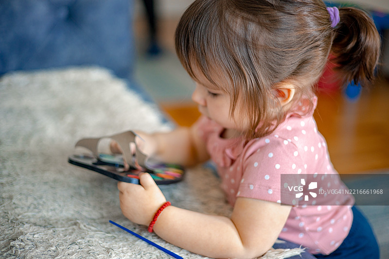 在家里，一个小女孩在画布上用水彩画画，享受着充满温暖和创造力的时刻，周围有画笔、色彩和想象力。图片素材