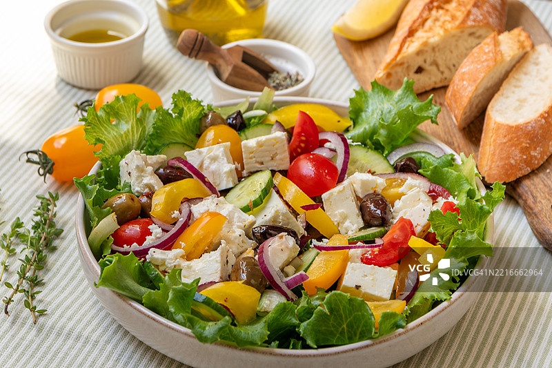 希腊沙拉，配有羊奶酪、新鲜番茄、罗勒、洋葱、橄榄和橄榄油，健康食品。图片素材