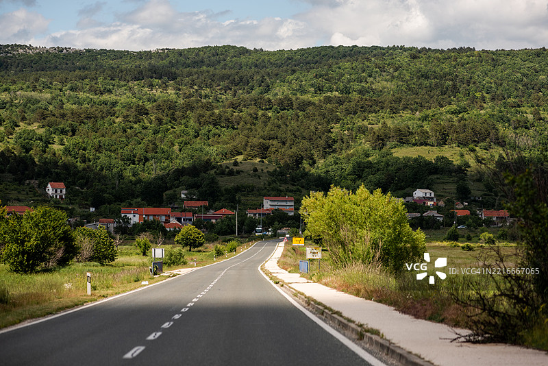 通往宁静村庄的风景道路，环绕在郁郁葱葱的山丘之间图片素材