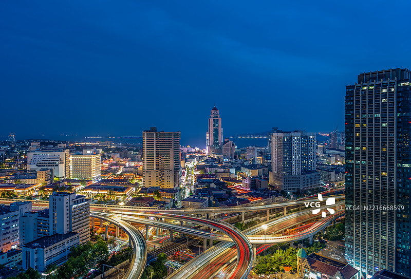 高角度视图：青岛市天际线前方高架道路的交通，黄昏时分。中国山东省青岛市图片素材
