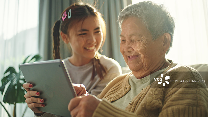 老年人与青少年一起在数字平板上玩游戏。图片素材