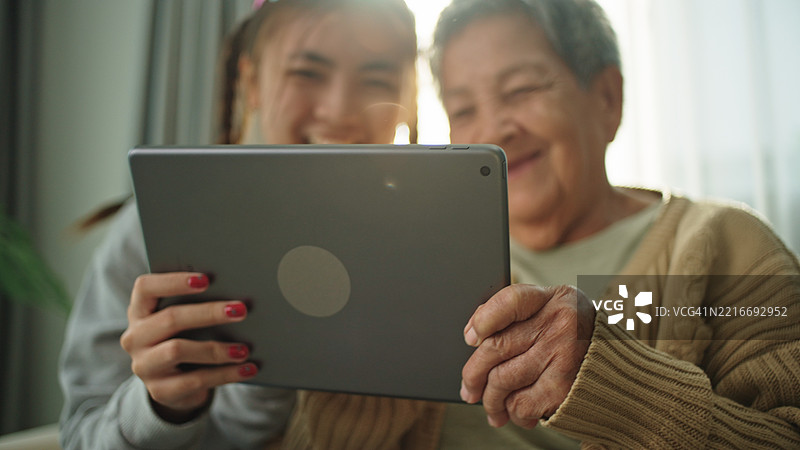 老年人与青少年一起在数字平板上玩游戏。图片素材
