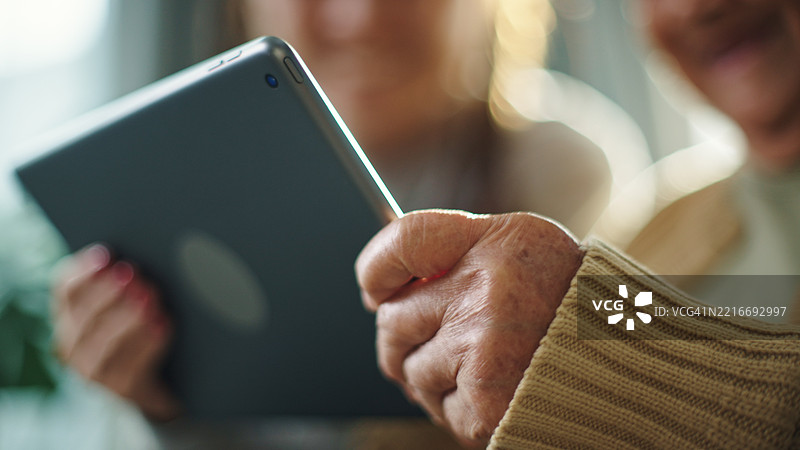 老年人与青少年一起在数字平板上玩游戏。图片素材