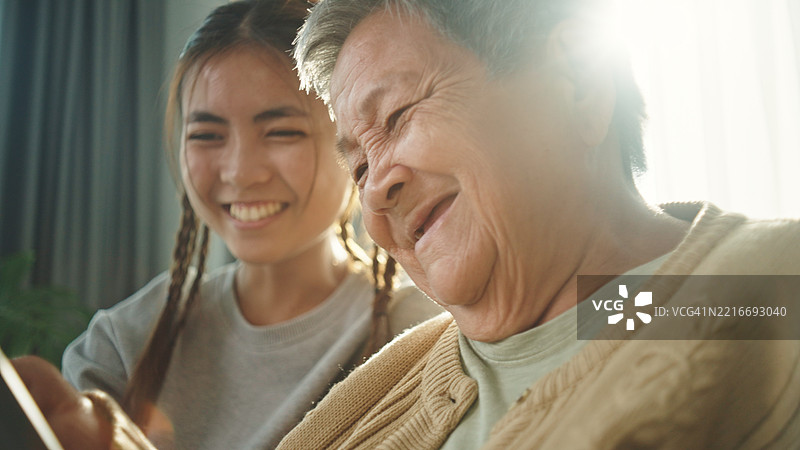 老年人与青少年一起在数字平板上玩游戏。图片素材