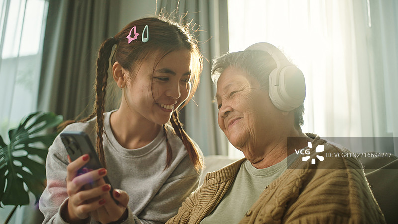 老年女性与年轻人一起放松聆听。图片素材
