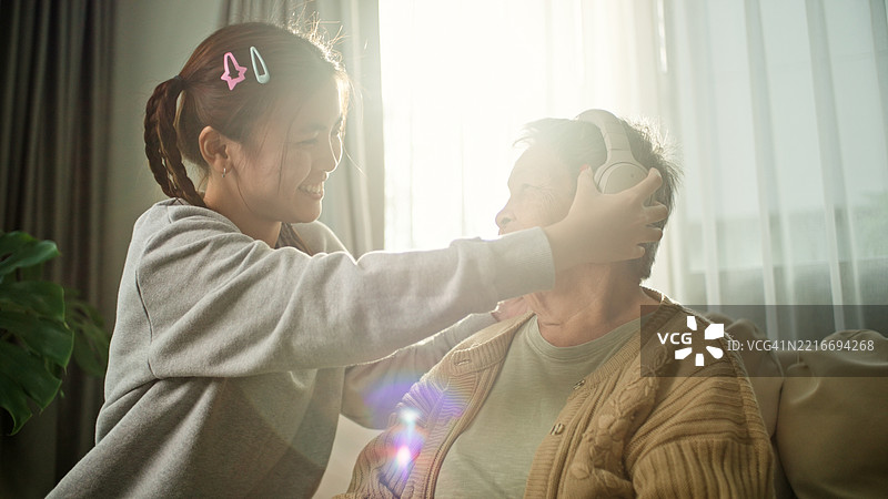 老年女性与年轻人一起放松聆听。图片素材