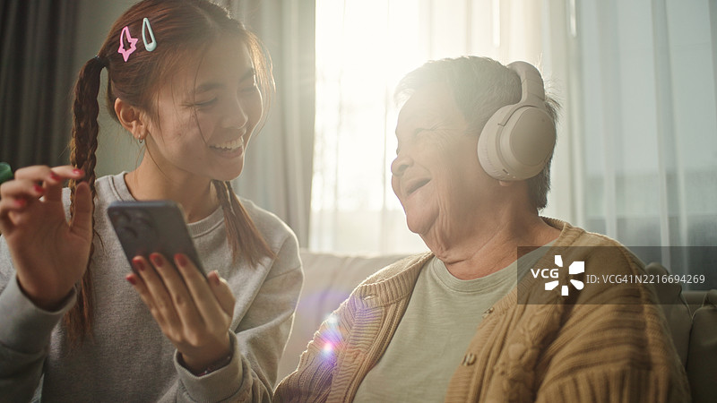 老年女性与年轻人一起放松聆听。图片素材