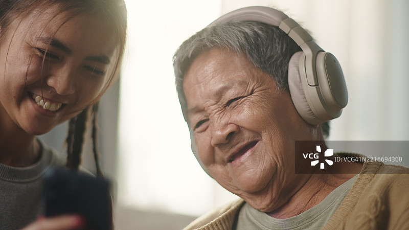 老年女性与年轻人一起放松聆听。图片素材