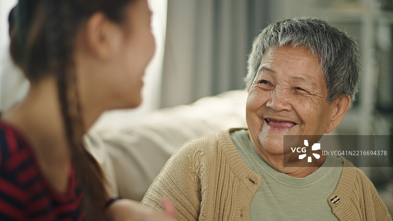 老年人与孙女在沙发上轻松交谈。图片素材