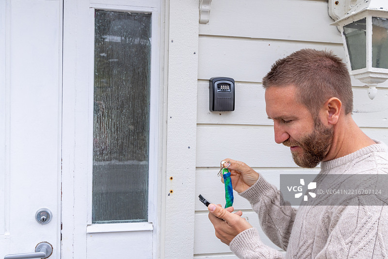 男子使用代码解锁户外钥匙保险箱图片素材