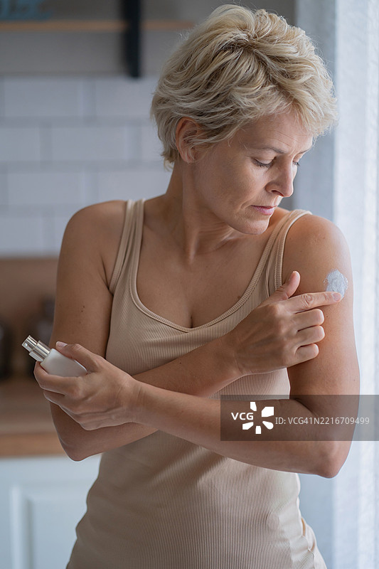 在明亮的厨房环境中涂抹雌激素霜，关爱肌肤图片素材