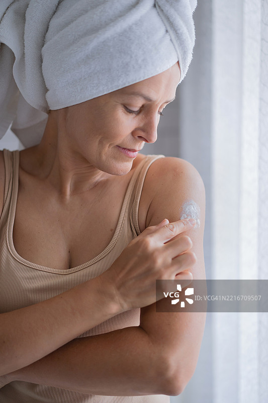 晨光柔和的女人用毛巾涂抹面霜图片素材