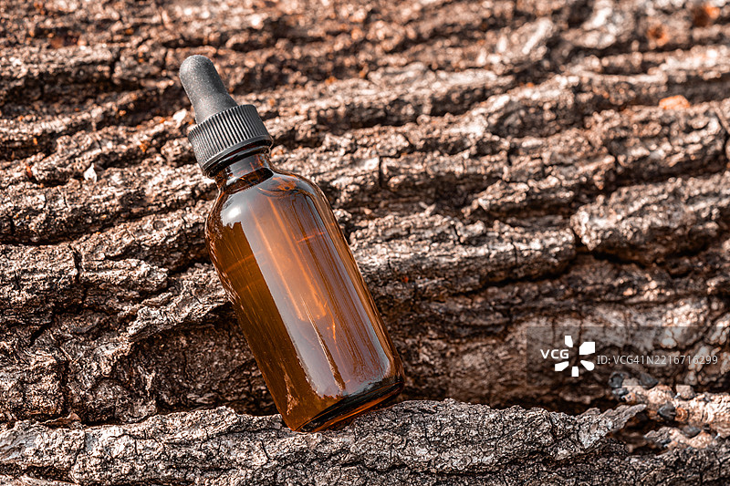 棕色滴管瓶置于纹理树皮背景上图片素材