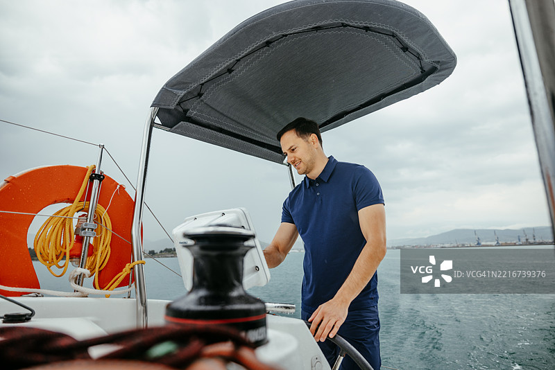 年轻的船长在阴天驾驶双体船图片素材