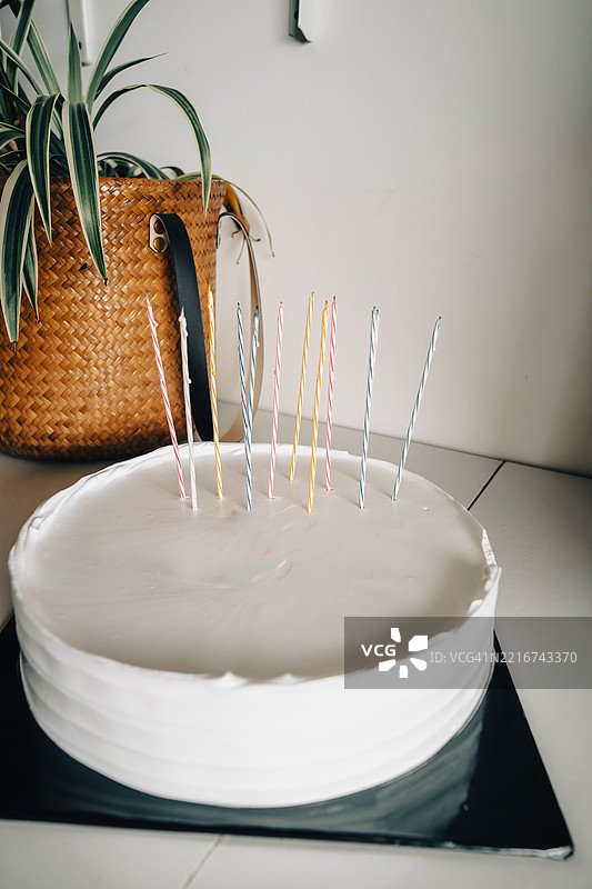 白色蛋糕上插着蜡烛，黑色蛋糕板和木质绿植背景下的空白背景，生日蛋糕展示图图片素材