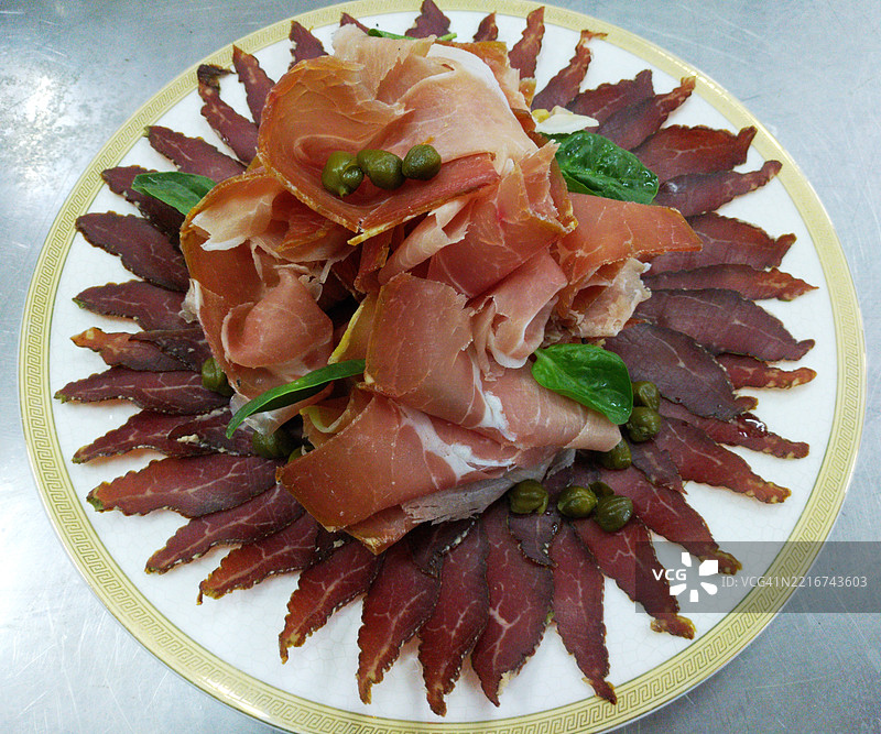 意大利美食：干腌火腿、干腌肉和香肠，摆放在圆形白色盘子上图片素材