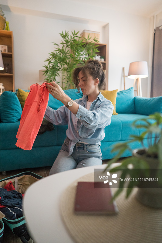 年轻女性在客厅里打包行李准备旅行图片素材