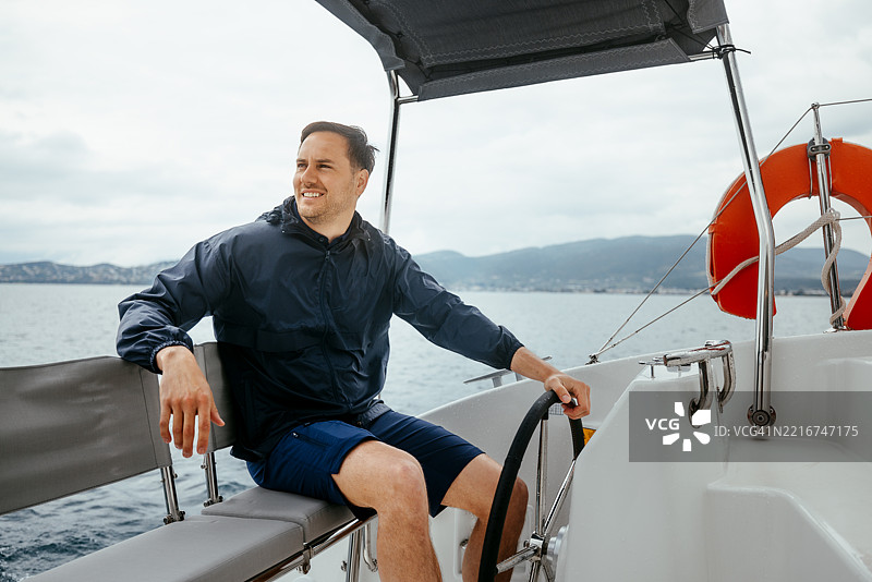 年轻的船长在阴天驾驶双体船图片素材