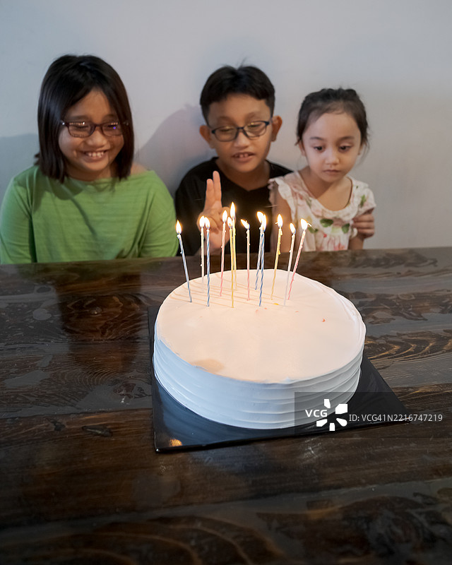 五彩缤纷的蜡烛点缀在白色蛋糕上，孩子们一起庆祝生日图片素材