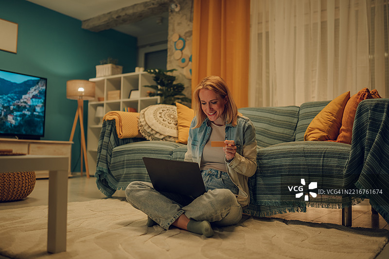 女性在家中使用笔记本电脑和信用卡进行在线购物图片素材