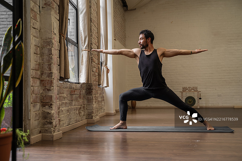 男子在室内练习战士二式瑜伽姿势图片素材